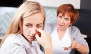 Hija adulta con gesto de angustia mientras su madre le recrimina, ejemplo de manipulación emocional en la familia