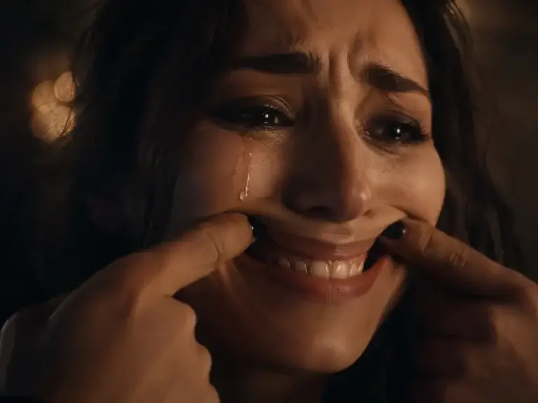 Mujer llorando mientras fuerza una sonrisa, como representación visual de la depresión funcional y el sufrimiento emocional oculto.